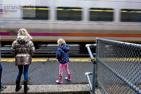 Zwei Mädchen beobachten und warten draußen am Bahnhof auf den Zug