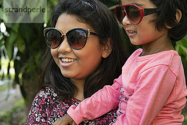 Schwestern tragen Sonnenbrillen und interagieren und machen Spaß im Freien