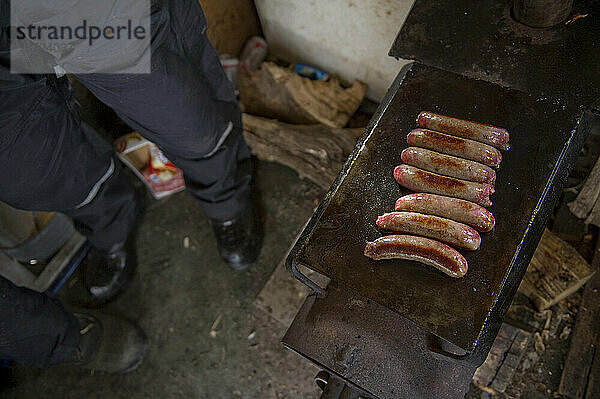 In einer gemütlichen  hausgemachten Eishütte am Lake Monona wird Bratwurst in einer Pfanne in Madison  WI  zubereitet.