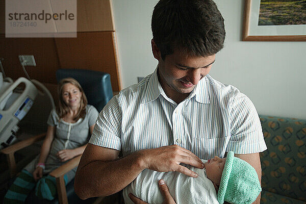 Ein Vater hält seine neugeborene Tochter am Tag nach ihrer Geburt.
