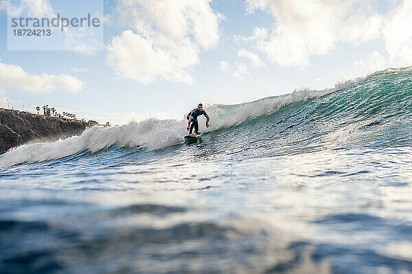 Surfer auf einer Welle vor klarem Himmel auf Teneriffa