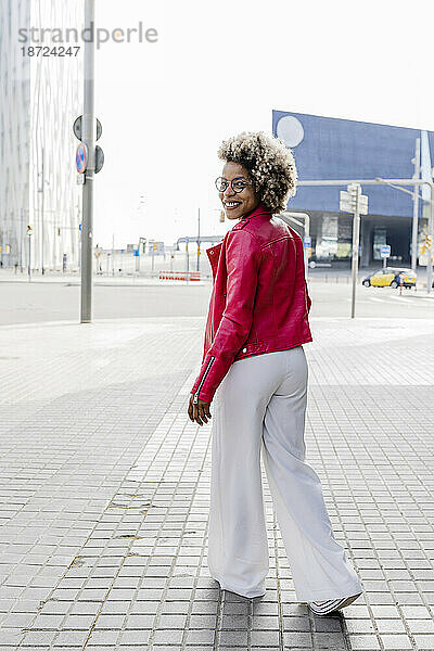 Rückansicht einer Frau in rosa Jacke  die die Straße entlang geht