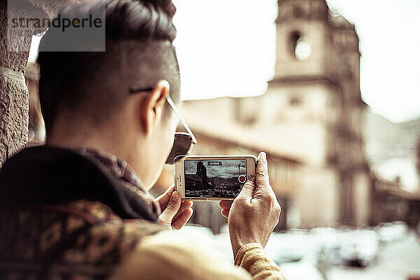 Androgyner Reisender macht mit dem Telefon ein Foto vom Kirchplatz