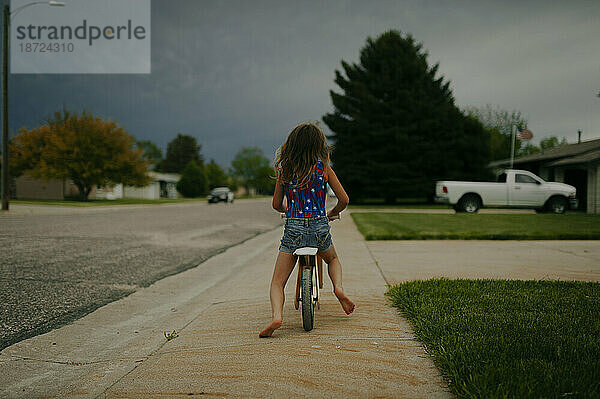 Mädchen fährt Fahrrad in stürmischer Sommernacht
