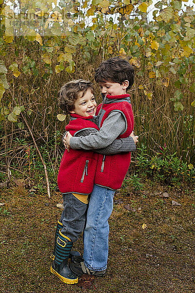 Zwei lächelnde kleine Jungen umarmen sich im Freien