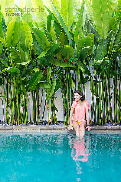 Junge Dame sitzt am Pool einer privaten Villa