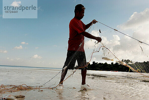 Eine Fischerfamilie entleert ihre Netze am Ufer.