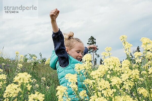 Junges Mädchen springt und lacht in einem Blumenfeld