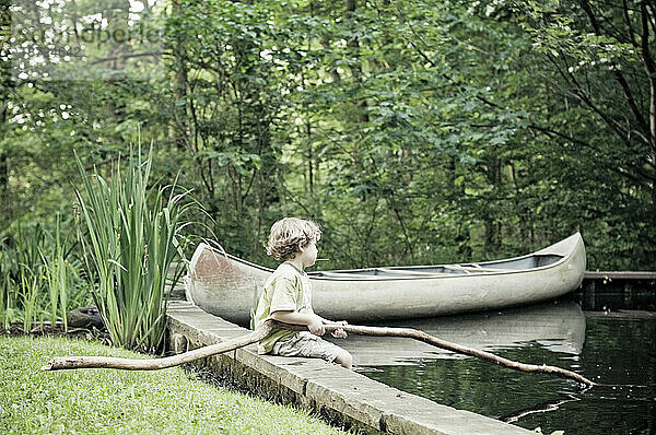 Ein kleiner Junge spielt in einem Teich.