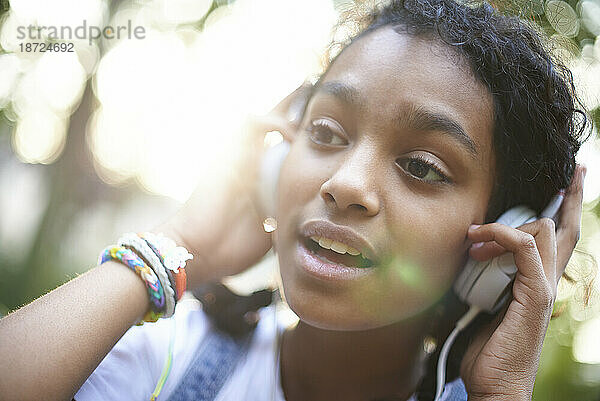 Schönes junges schwarzes Teenagermädchen mit Kopfhörern  das draußen läuft