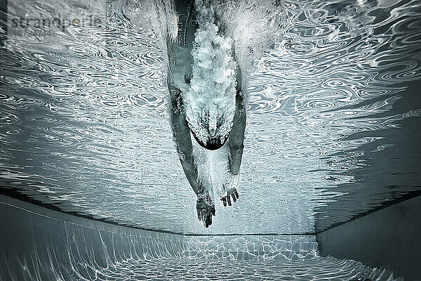 Ein Mann springt in einen Pool  um Bahnen zu schwimmen.