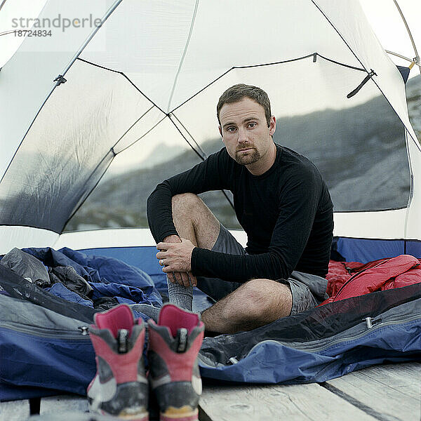 Ein Mann posiert für ein Porträt in einem Zelt in den Bergen.
