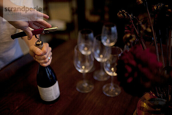 Eine Frau öffnet während einer Dinnerparty in ihrem Haus in Ventura  Kalifornien  eine Flasche Wein.