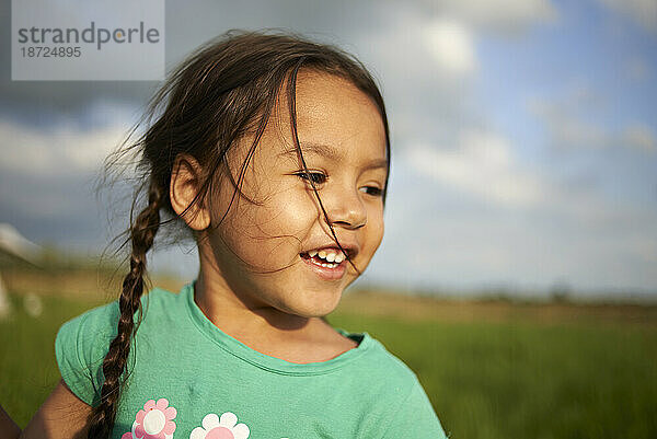 Kopfbild eines süßen jungen asiatischen Mädchens  das glücklich in der Sommersonne lächelt