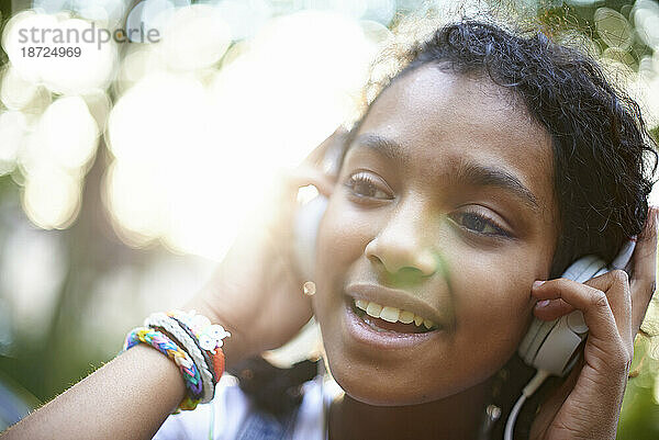 Schönes junges schwarzes Teenagermädchen mit Kopfhörern  das draußen läuft