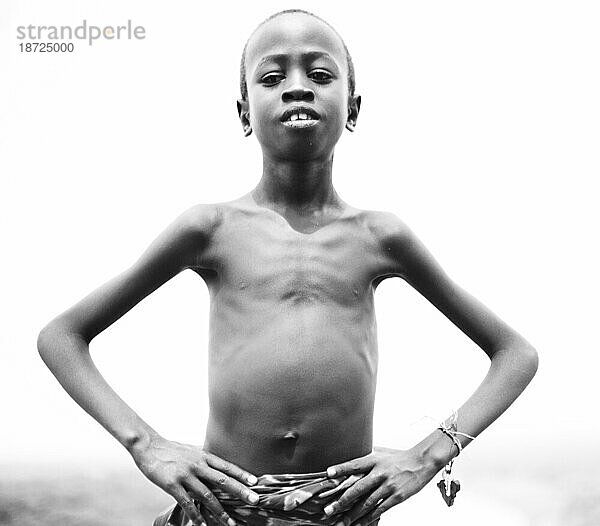 Ein Porträt eines kleinen Jungen mit den Armen in den Hüften im Omo-Tal  Äthiopien. (Schwarz und weiß)