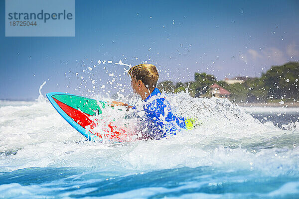 Junger Surfer  glücklicher kleiner Junge im Meer auf Surfbrett