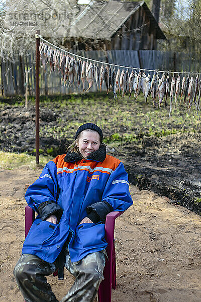 Porträt einer blonden Frau  die im Wintermantel auf einem Stuhl sitzt  Tichwin  Sankt Petersburg  Russland