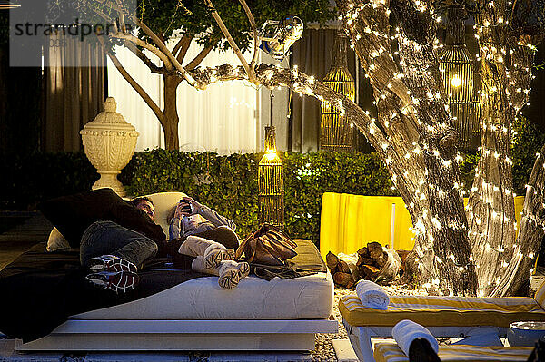 Ein Paar entspannt sich in der Dämmerung im Spa im Freien auf einem Loungebett.