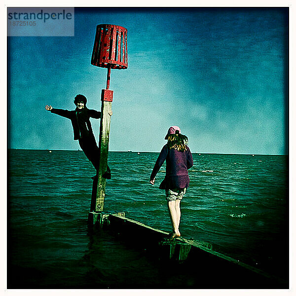 Zwei Kinder spielen auf einem Steg über dem Meer in Cleethorpes England UK Europe