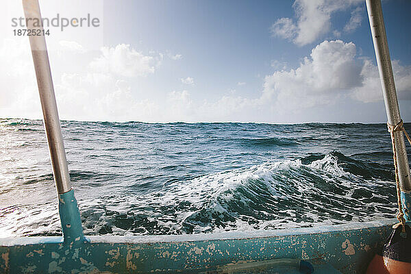 Eine kleine Welle draußen auf dem Meer wird von einem Hochseefischerboot umrahmt
