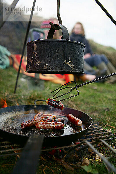 Eine Familie grillt Würstchen und kocht Wasser am Lagerfeuer in der Nähe von Ellingstring  North Yorkshire  England  Großbritannien  am 22. März 2009.