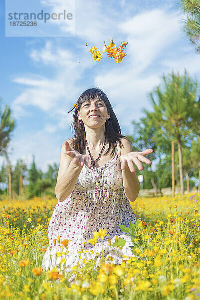 Fuß einer jungen Frau mit einer Frühlingsblume in den Fingern  die auf einer sonnigen  warmen Wiese liegt.