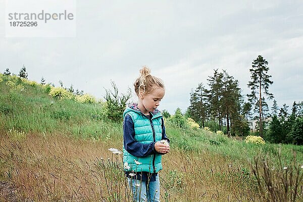 Ein junges Mädchen stand auf einem Feld und hielt einen Blumenstrauß in der Hand