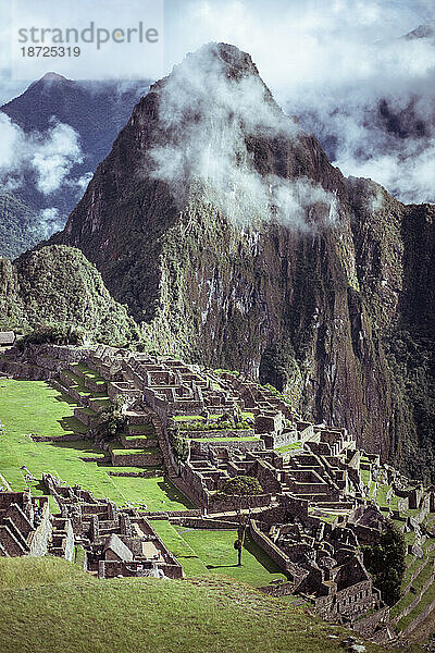 Epischer Blick auf die Berge in den Wolken hinter den Ruinen der Inkastadt Machu Picchu