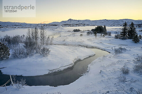 Ruhiger Fluss im verschneiten Tal im Winter
