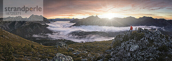 Mann Beobachten Sie Nebel bei Sonnenaufgang von der Spitze einiger Berge