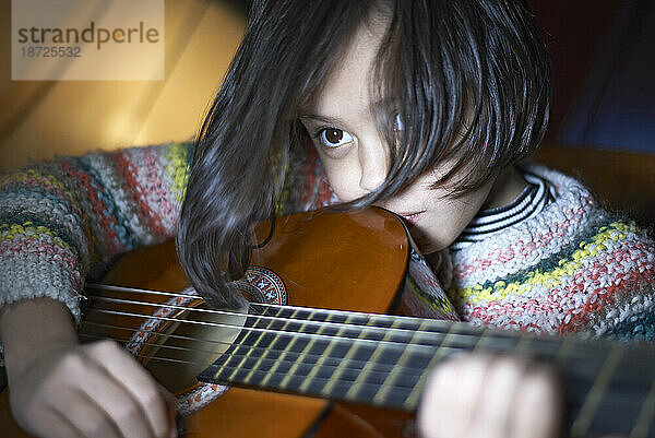 Junges asiatisches Mädchen  das Akustikgitarre spielt und ein Lied schreibt