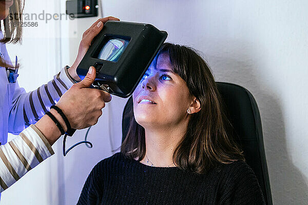 Augenarzt untersucht die Augen einer Patientin mit ultraviolettem Licht