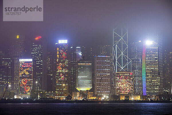 Nachts beleuchtete Bürogebäude in Hongkong  China. Diese dicht besiedelte Stadt hat einen enormen CO2-Fußabdruck.
