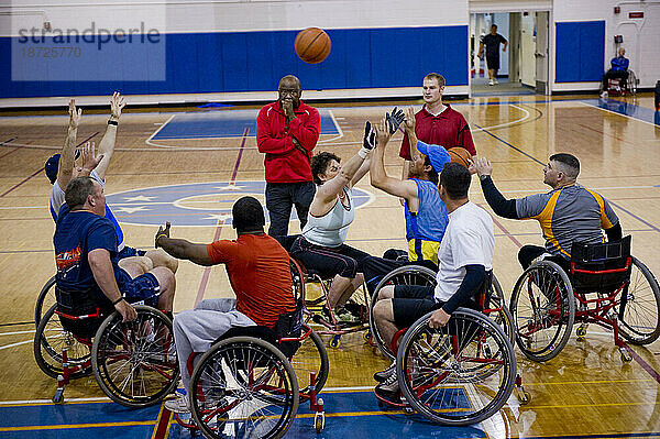 Ein Trainer wacht während des Rollstuhlbasketballtrainings über ein Rollstuhlbasketball-Duell.