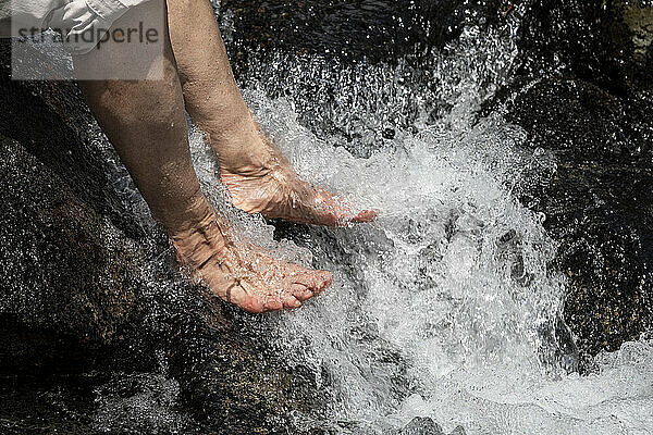 Detailansicht von Frauen  die müde Füße in einem kalten Alpenfluss kühlen