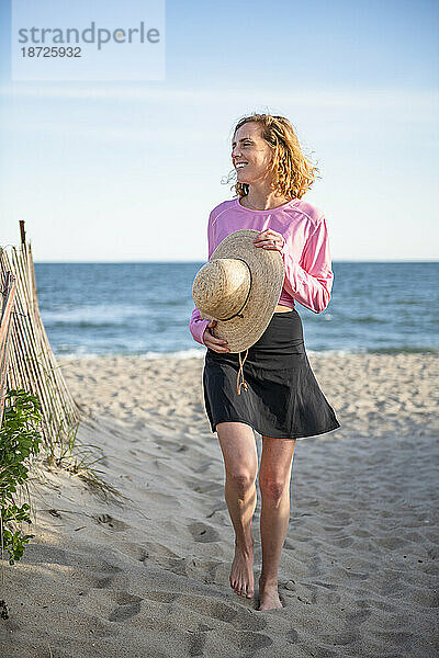 Frau in UPF-Sonnenschutzkleidung beim Strandspaziergang