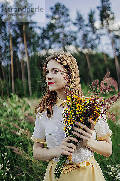 Frau im Wald mit einem Blumenstrauß in den Händen
