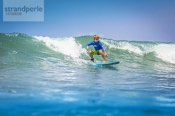 Junger Surfer  glücklicher kleiner Junge im Meer auf Surfbrett