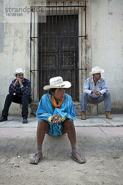 Ein Tarahumara-Läufer sitzt mit zwei mexikanischen Männern