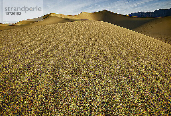 Linien verlaufen durch den Sand der Eureka-Sanddünen  während die Sonne über dem Death Valley in Kalifornien aufgeht.