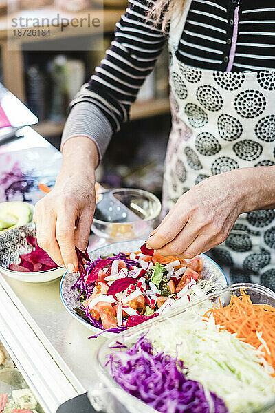 Frau bereitet Salat in einem veganen Restaurant zu