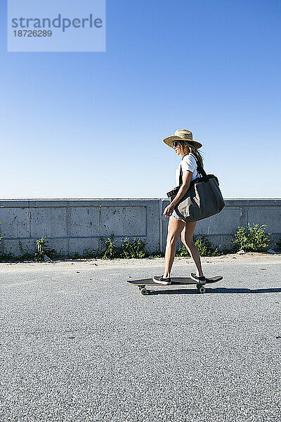 Frau fährt Skateboard für einen Strandtag in Neuengland