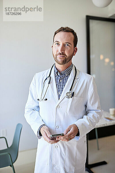 Porträt eines männlichen Mitarbeiters im Gesundheitswesen  der im Stehen einen Laborkittel trägt