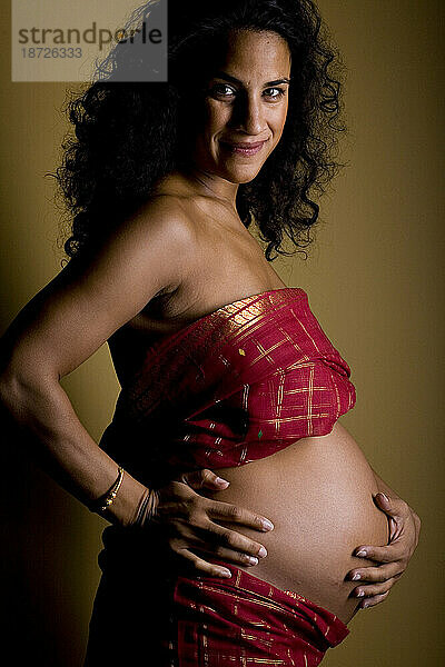 Ein Porträt einer lächelnden Frau  die im siebten Monat schwanger ist.