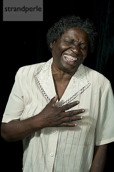 Eine ältere schwarze jamaikanisch-kanadische Frau lacht herzlich im Stehen.