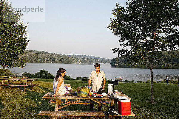 Ein junges Paar genießt ein Picknick in einem State Park in der Nähe eines Sees.