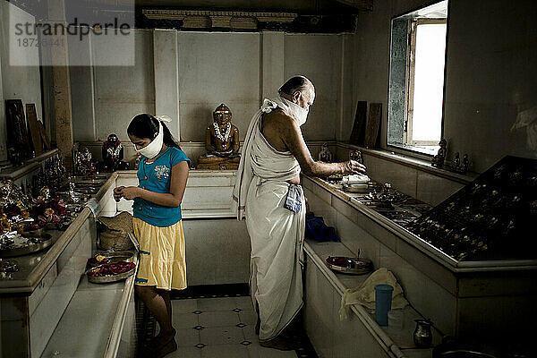 Ein junges Mädchen und ein alter Mann beten in einem Jain-Tempel.