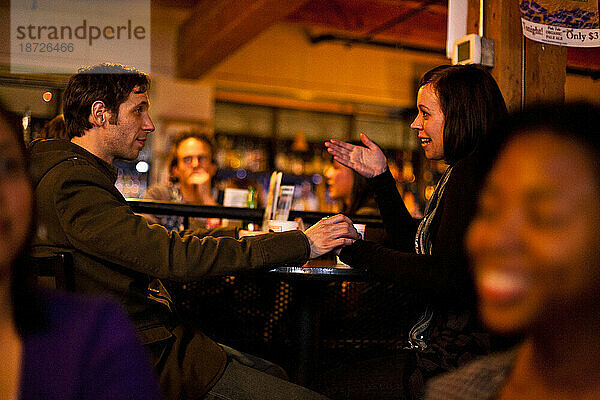 Ein junger  stilvoller Mann hält während eines Gesprächs in einer Bar in Seattle  Washington  die Hand einer Frau.
