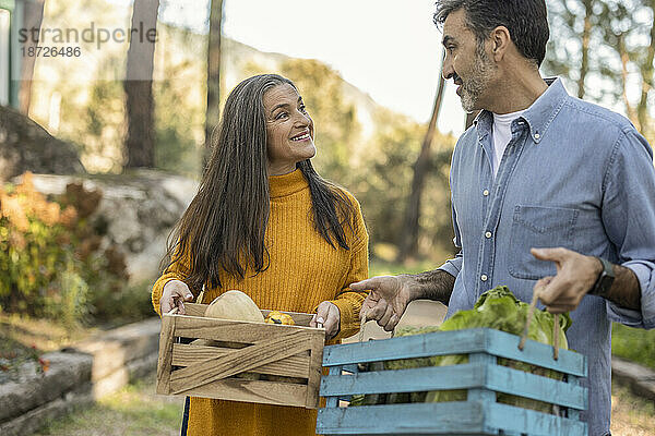 Man and woman carrying crates with freshly harvested organic vegetables
